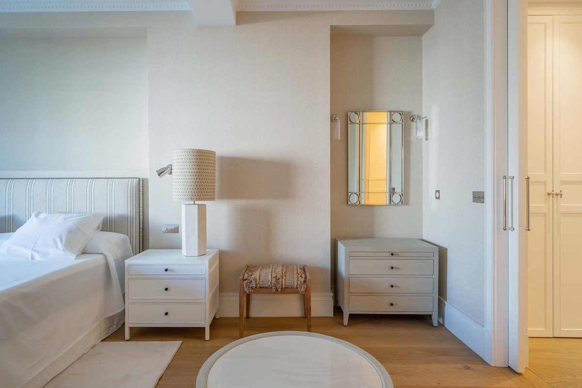 Dormitorio con mesillas lacadas, cómoda y espejo entre apliques